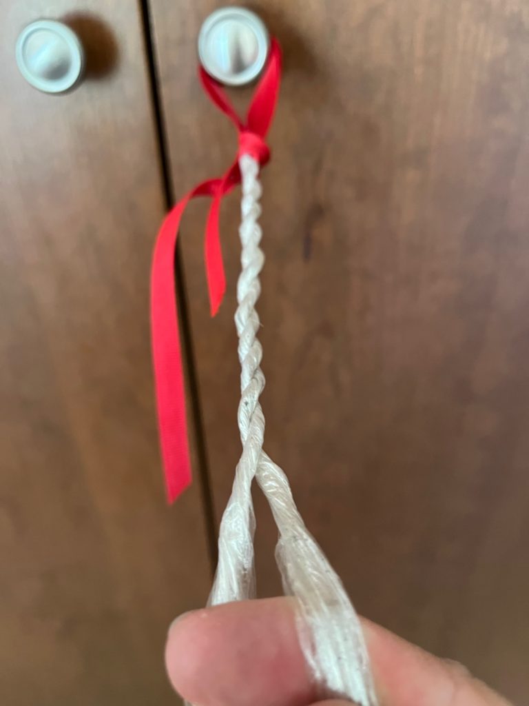 twined saran wrap to start a rope tied with red ribbon to door handle