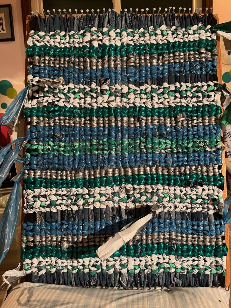 Nail loom with rug of white, light green, dark green, blue.  