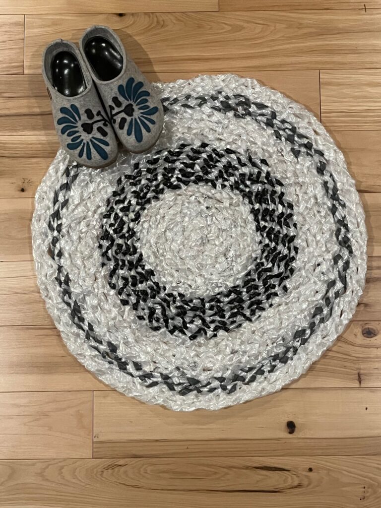 Braided rug in white, black and grey with shoes to show size